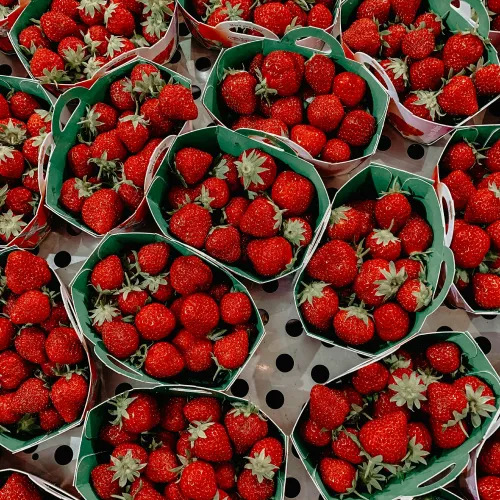 A collection of fresh strawberries in green baskets.