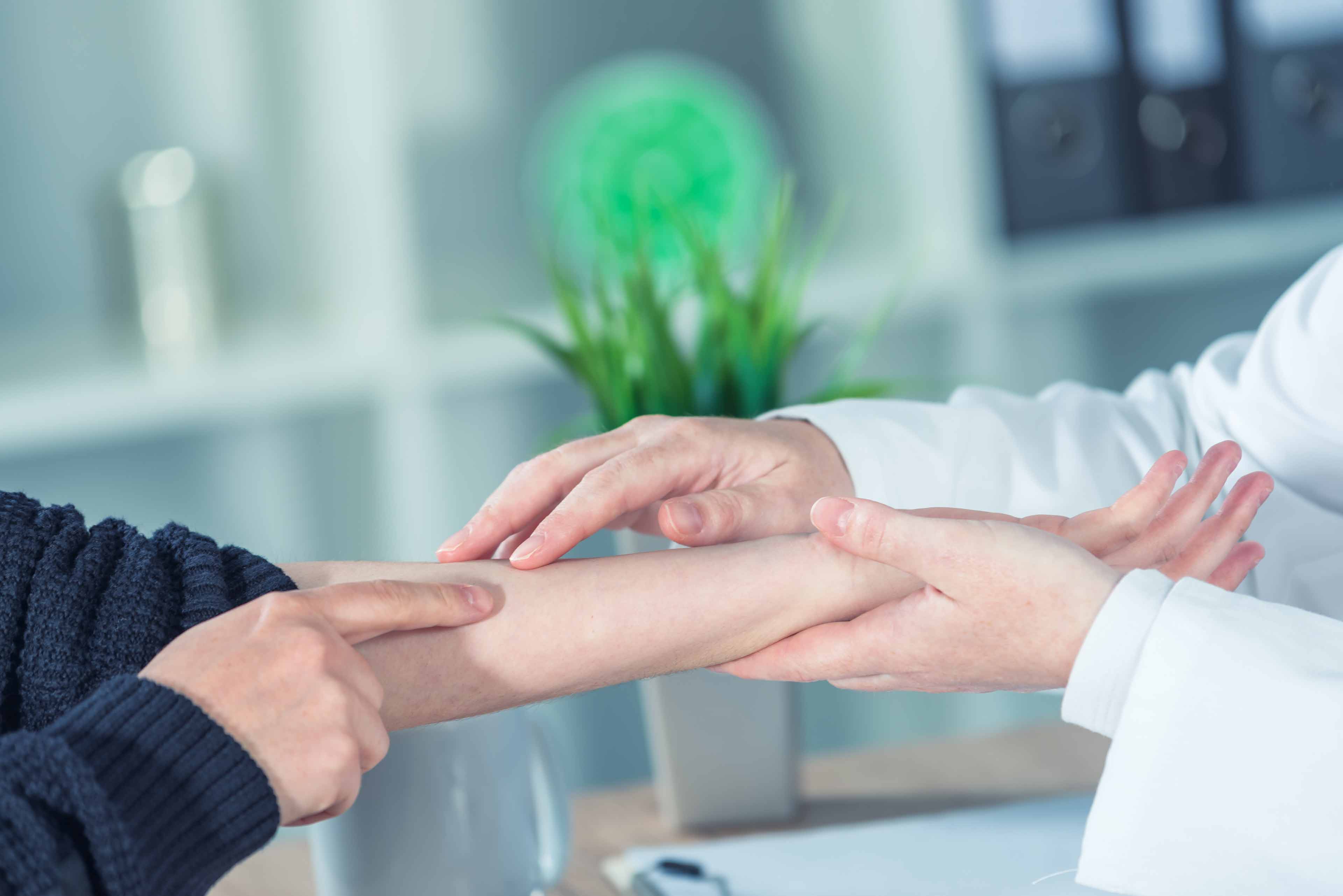 a person pointing to their arm while a doctor holds their wrist