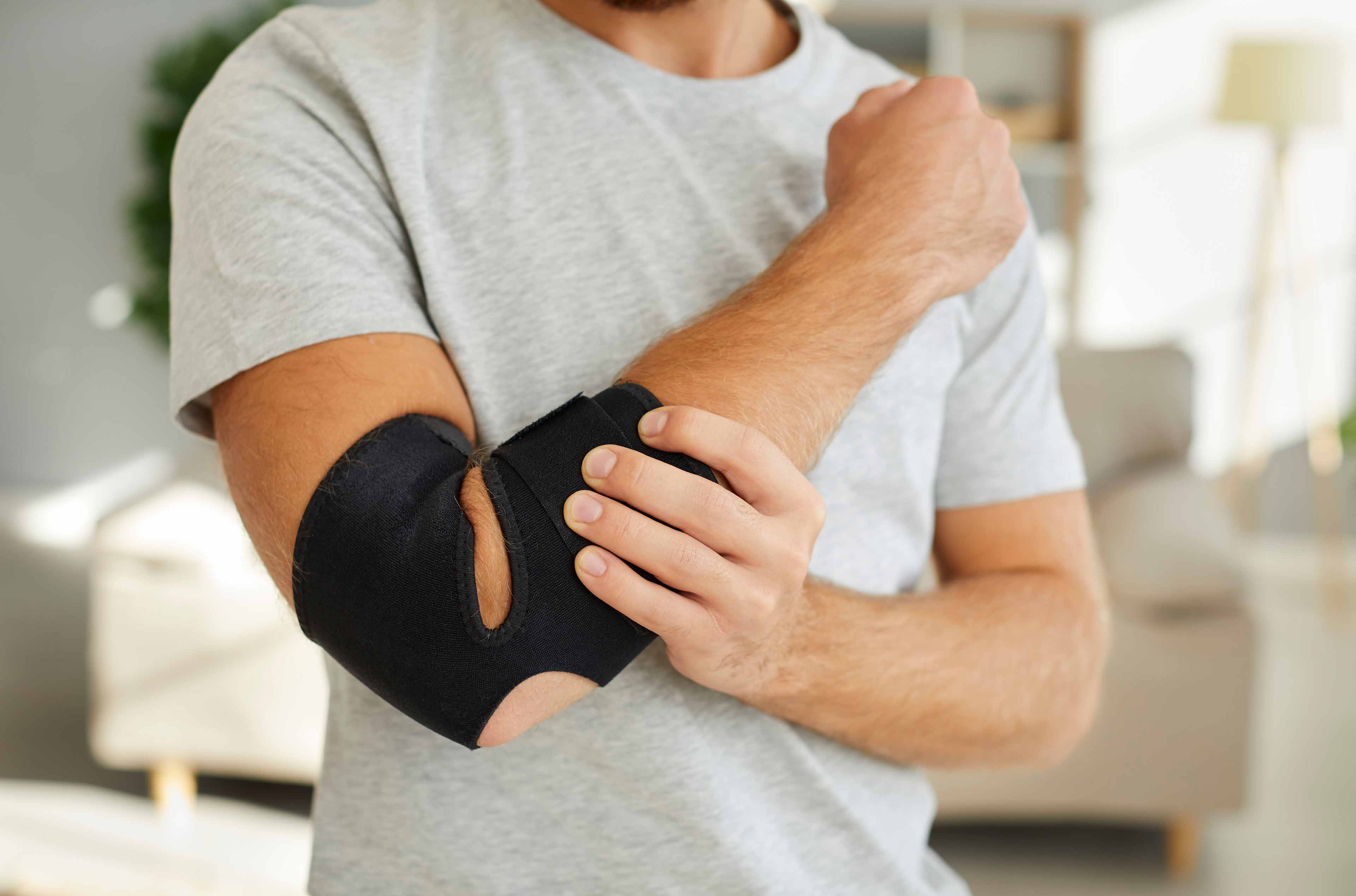 A person holding their forearm with a brace on their elbow