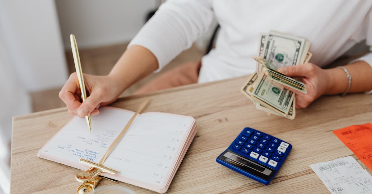 Hôtelier calculant le coût réel des commissions Booking.com avec calculatrice et documents financiers