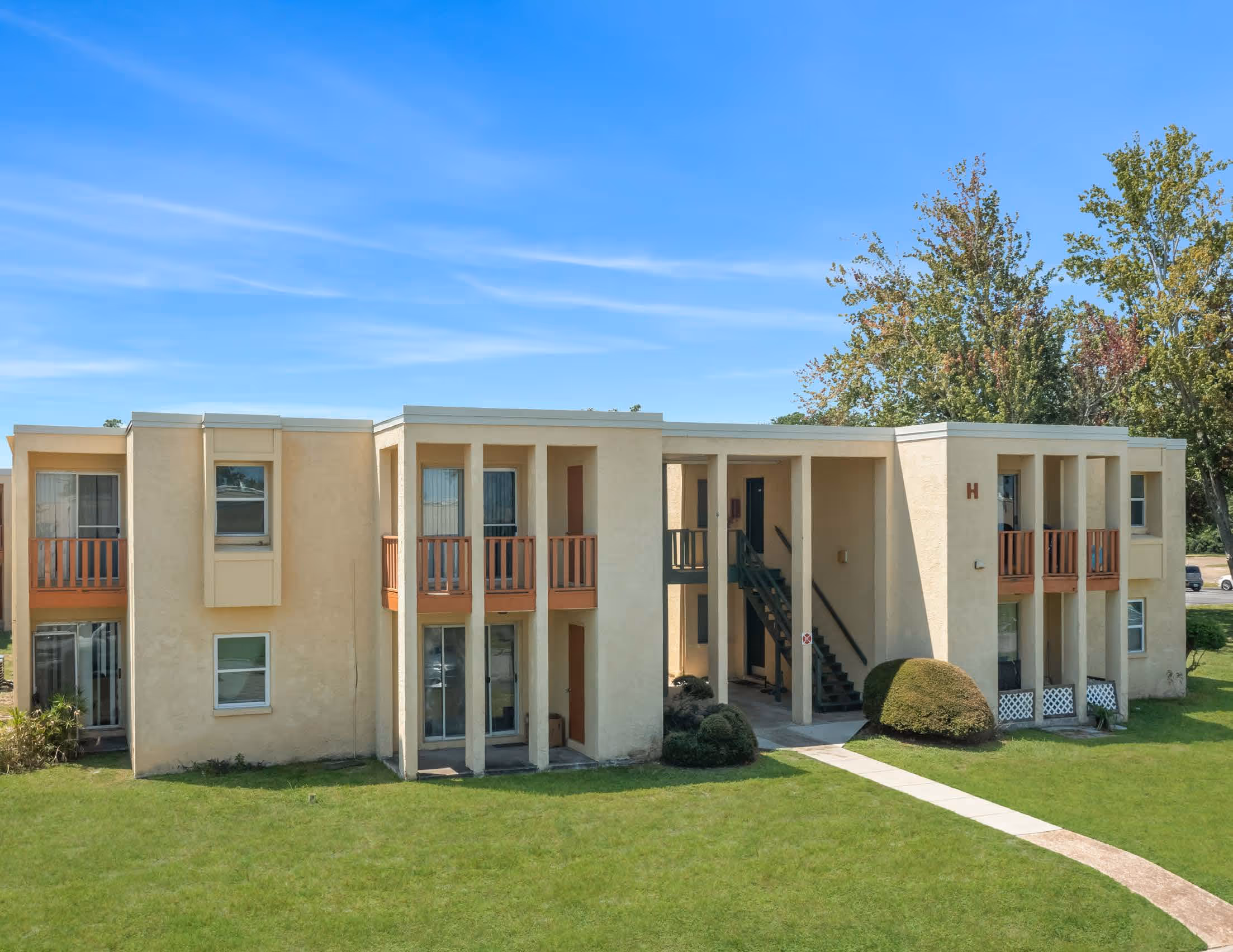 Aztec Villa Apartments exterior with green lawn and blue sky