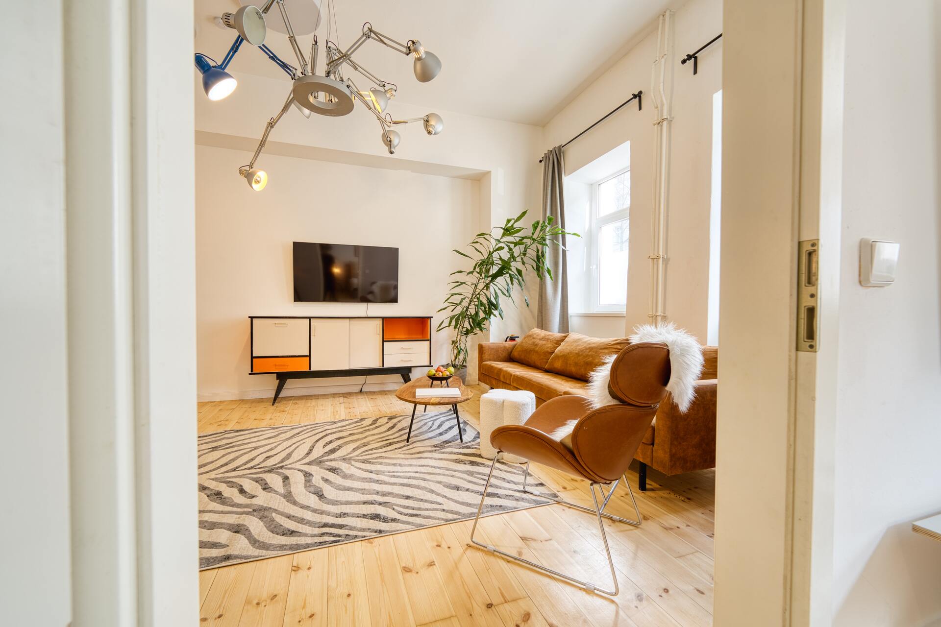 Wohnzimmer mit Designerlampe und Blick auf den TV-Bereich