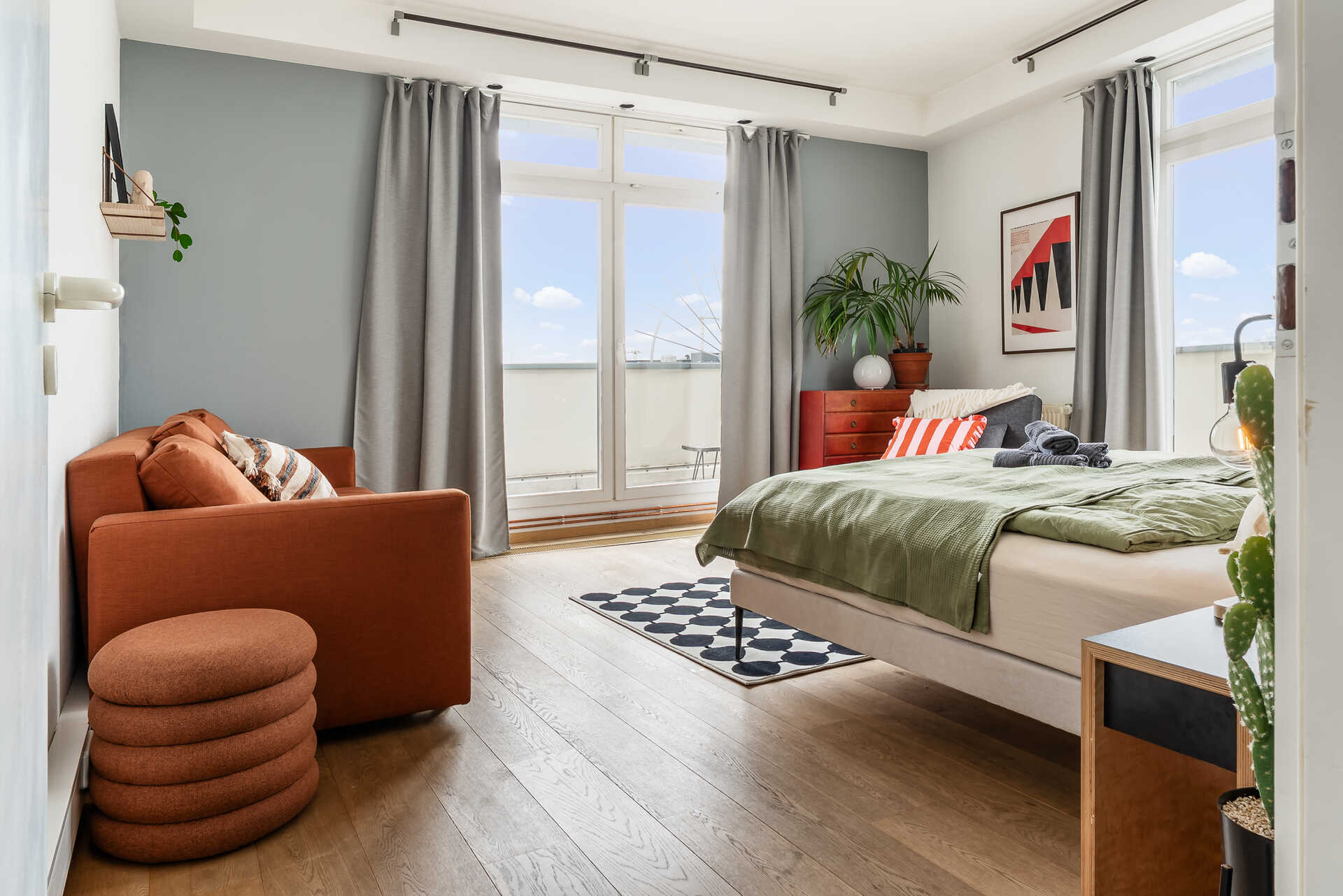 Schlafzimmer mit Bett und Schlafsofa und Blick auf den Balkon