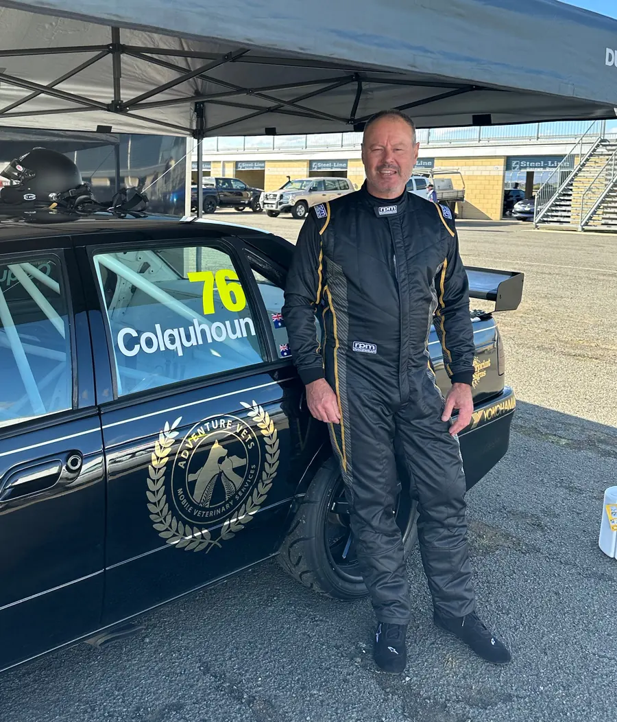 Andrew in racing overalls beside his number 76 race car