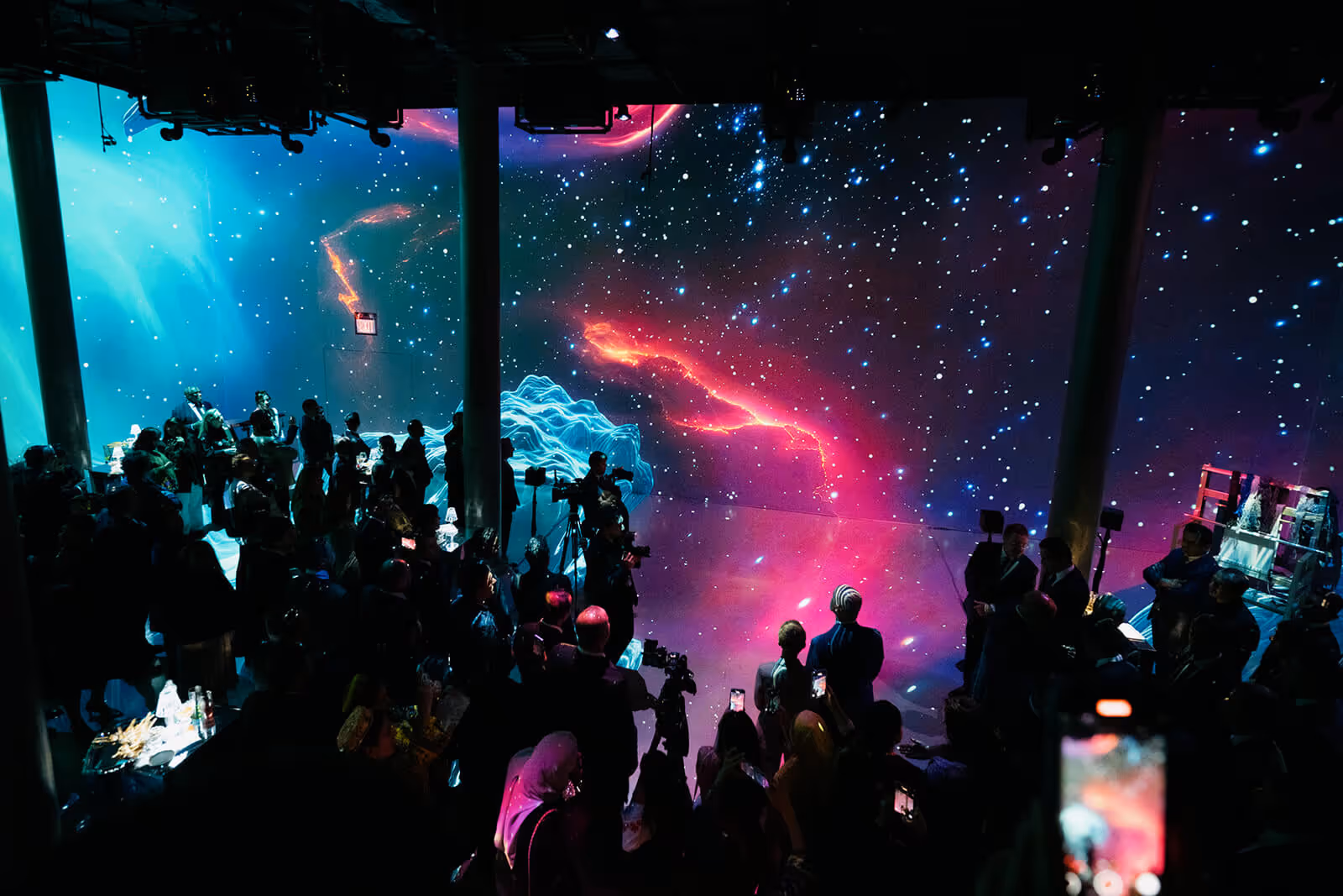 Immersive show: audience viewing starry projection with neon trails.