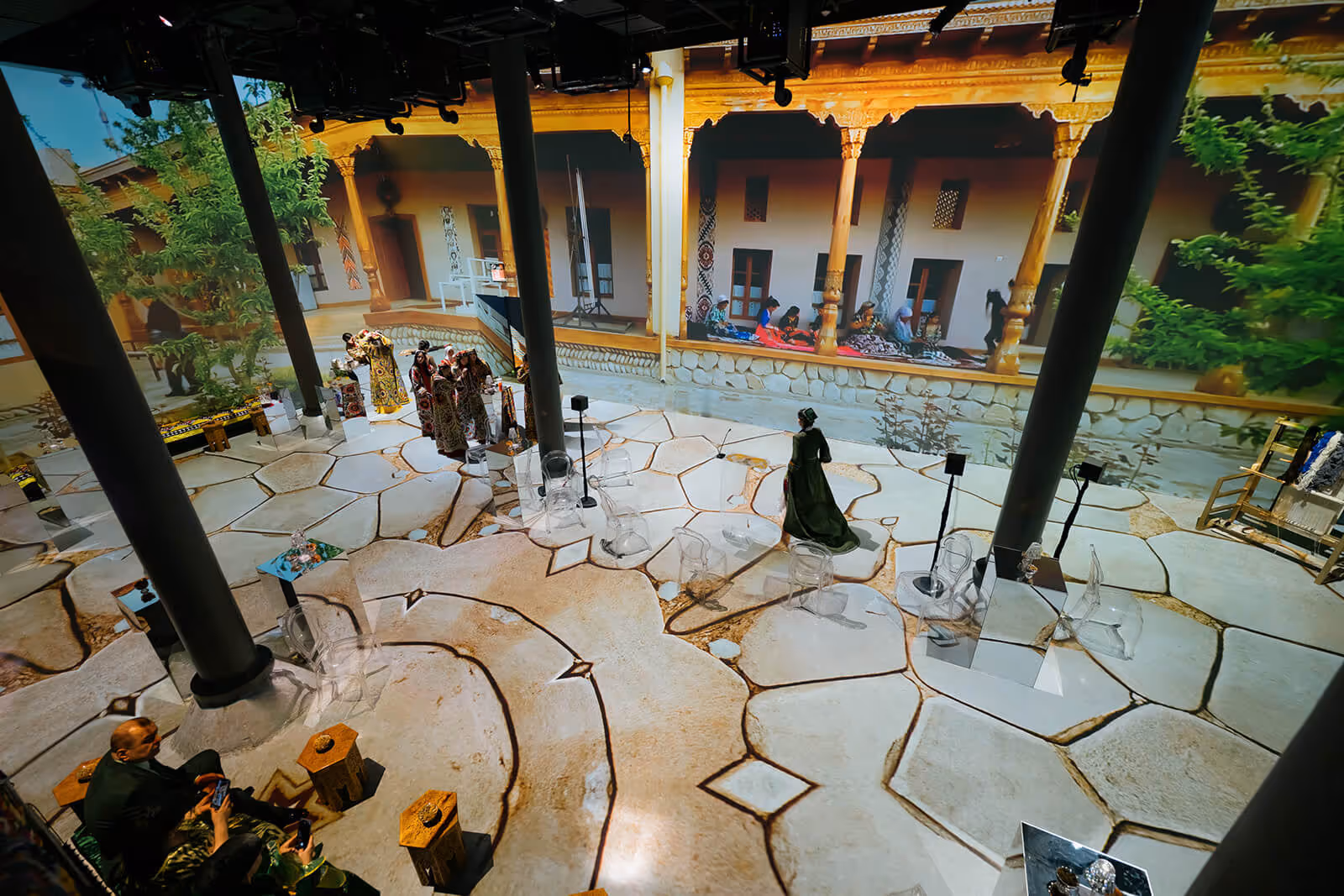 Digital exhibit: visitors in projected courtyard with Tajik elements and greenery.
