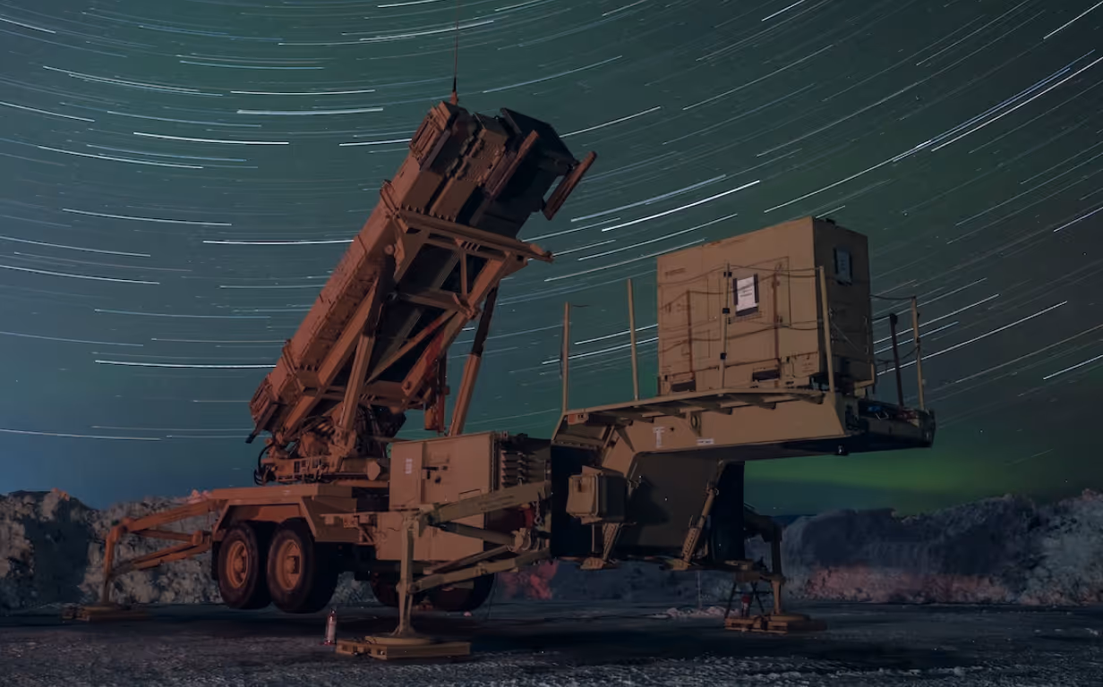 Military missile launcher vehicle positioned outdoors under a night sky with visible star trails.