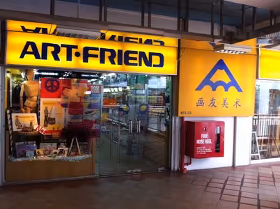 Entrance of Art Friend store with yellow signage and glass doors showing art supplies inside.