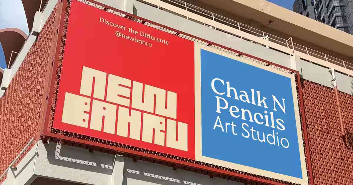 Outdoor billboard on a building corner displaying a red panel with 'NEW BAHRU' and a blue panel with 'Chalk N Pencils Art Studio'.
