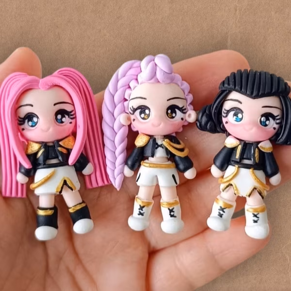 Three small dolls with big eyes and colorful hair in black and white outfits on a hand.