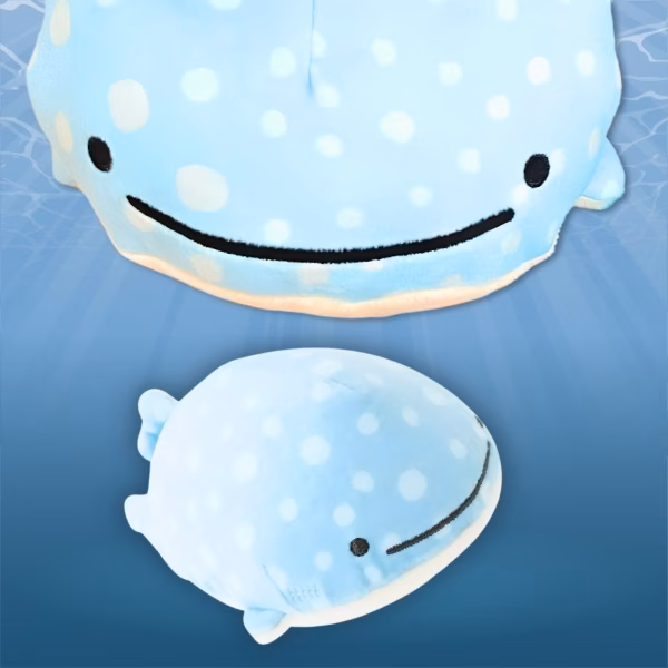 Two light blue plush whale shark toys with white spots and smiling faces on a blue background.