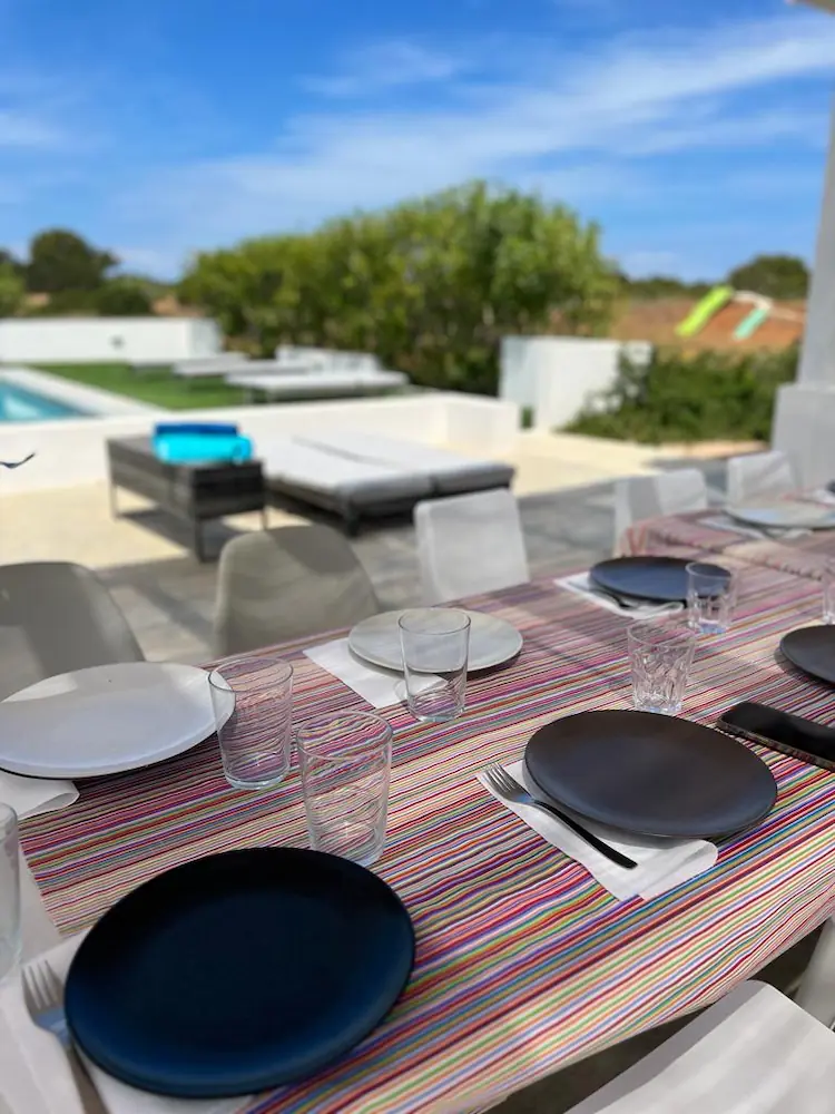 Mesa puesta en la terraza exterior lista para disfrutar de una cena de verano al aire libre.