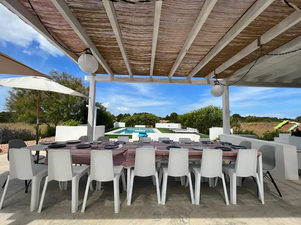 Porche cubierto con gran mesa de comedor exterior ideal para comidas familiares en la villa.