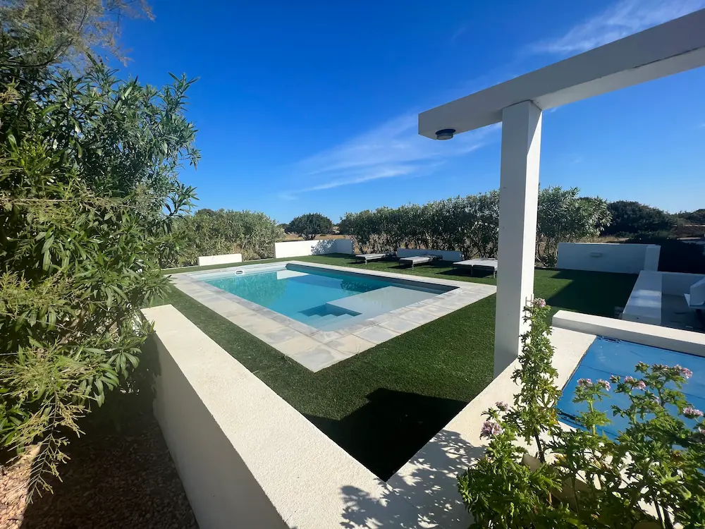 Piscina privada de agua cristalina rodeada de jardín y zona chill-out en la villa Can Javi de Palma.