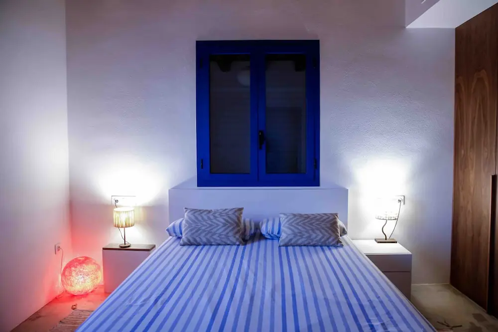 Cama queen en el dormitorio principal suite con textiles naturales en Formentera