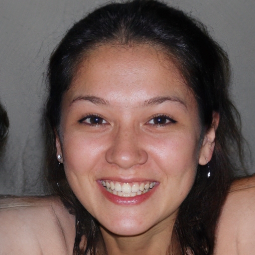 Close-up of a smiling young woman with dark hair, clear skin, and wearing small hoop earrings.