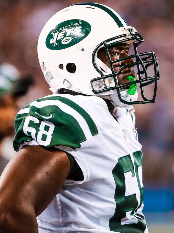 Close-up of Kelvin as a New York Jets football player wearing a white helmet and jersey with number 58 and a green mouthguard.