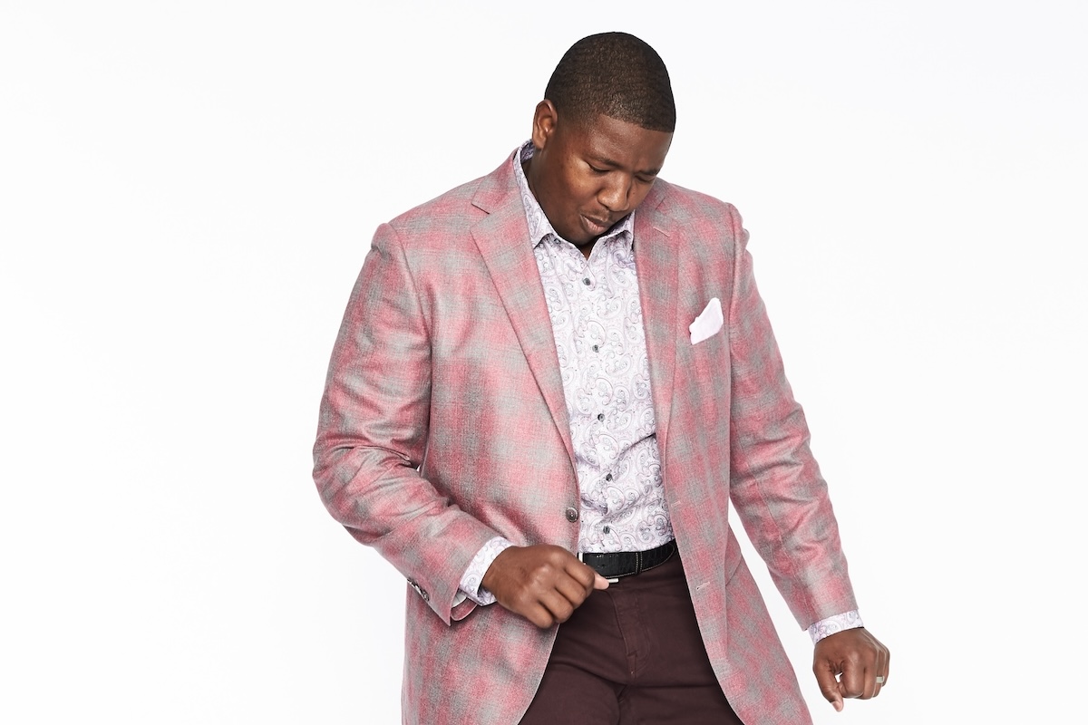 Kelvin wearing a pink and gray checkered blazer with a white paisley shirt and dark pants.