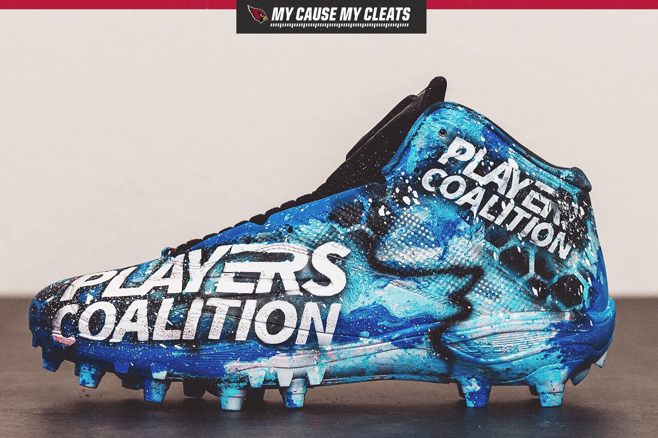 Blue football cleat with abstract paint design and large white text reading 'PLAYERS COALITION'.