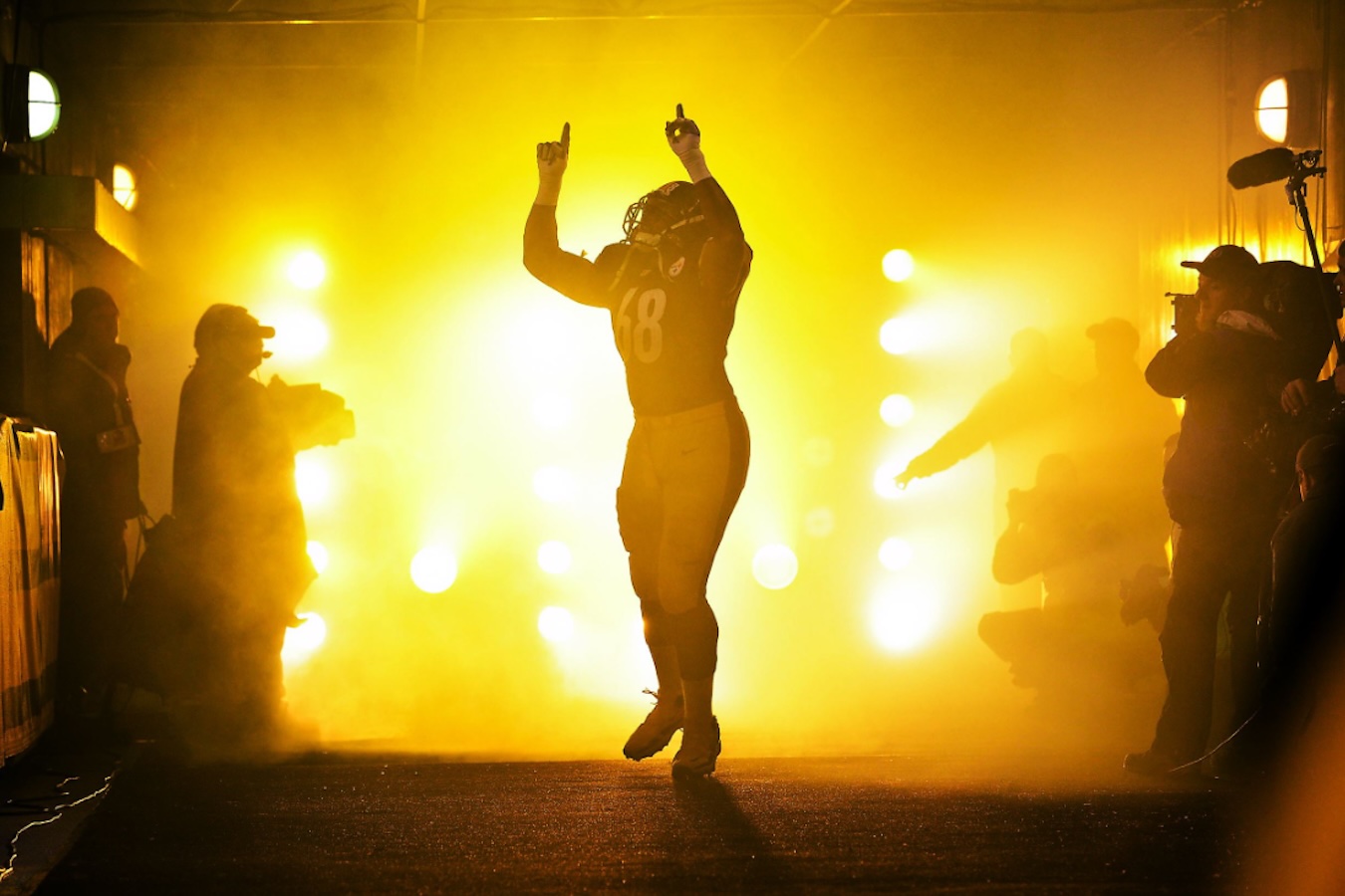 Kelvin wearing number 68 raises both hands with index fingers pointing up amid yellow fog and bright tunnel lights.