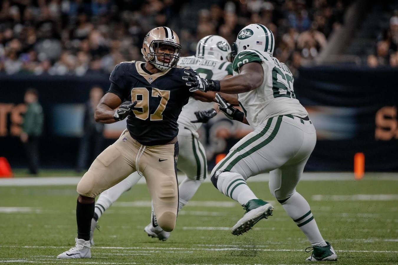 New Orleans Saints player number 97 engaging with Kelvin as a New York Jets offensive lineman during a football game.