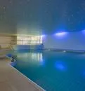 Das Hallenbad von Holmes Place verfügt über blaue Beleuchtung und natürliches Tageslicht durch große Fenster.