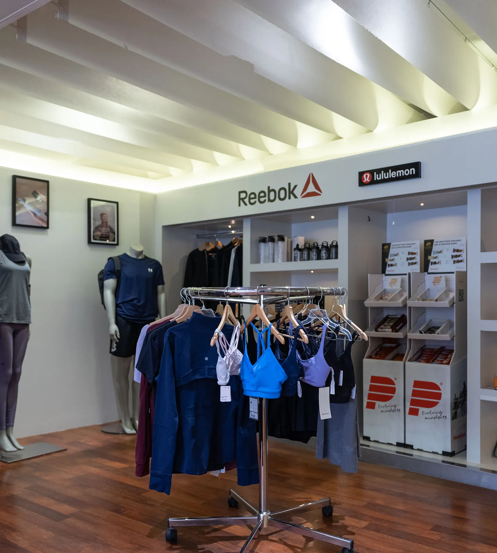 Schaufenster für Sportbekleidung im Holmes Place-Geschäft mit Kleidung und Accessoires auf Ständern und Regalen.