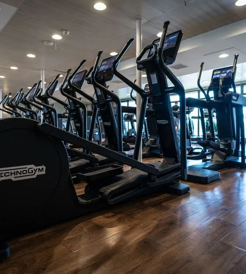 Fitnessstudio von Holmes Place mit schwarzen Crosstrainern und Ellipsentrainern von Technogym mit modernen Touchscreens.