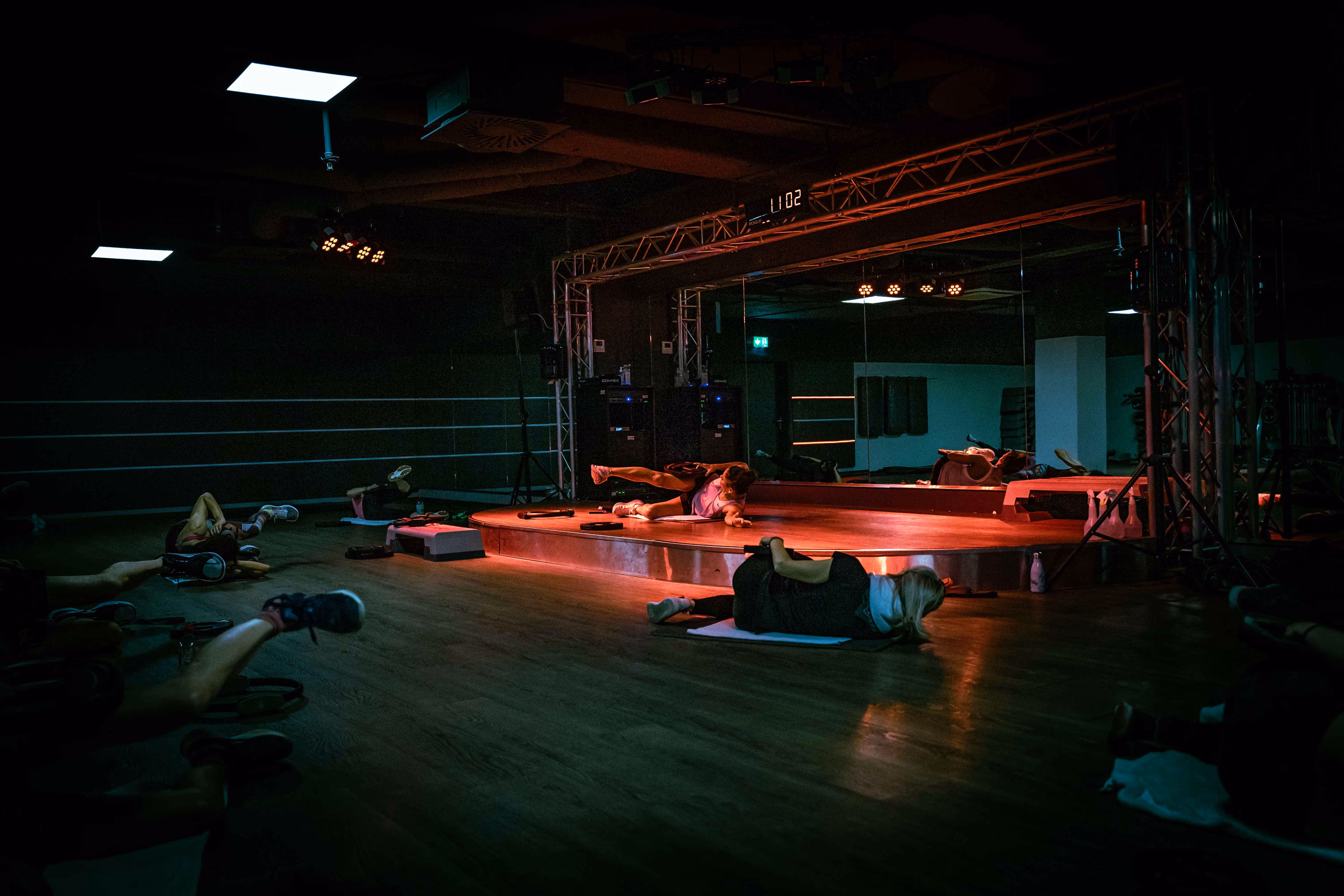 Bahnbrechendes Fitnessprogramm bei Holmes Place: Mitglieder praktizieren Yoga in einem schwach beleuchteten Studio.