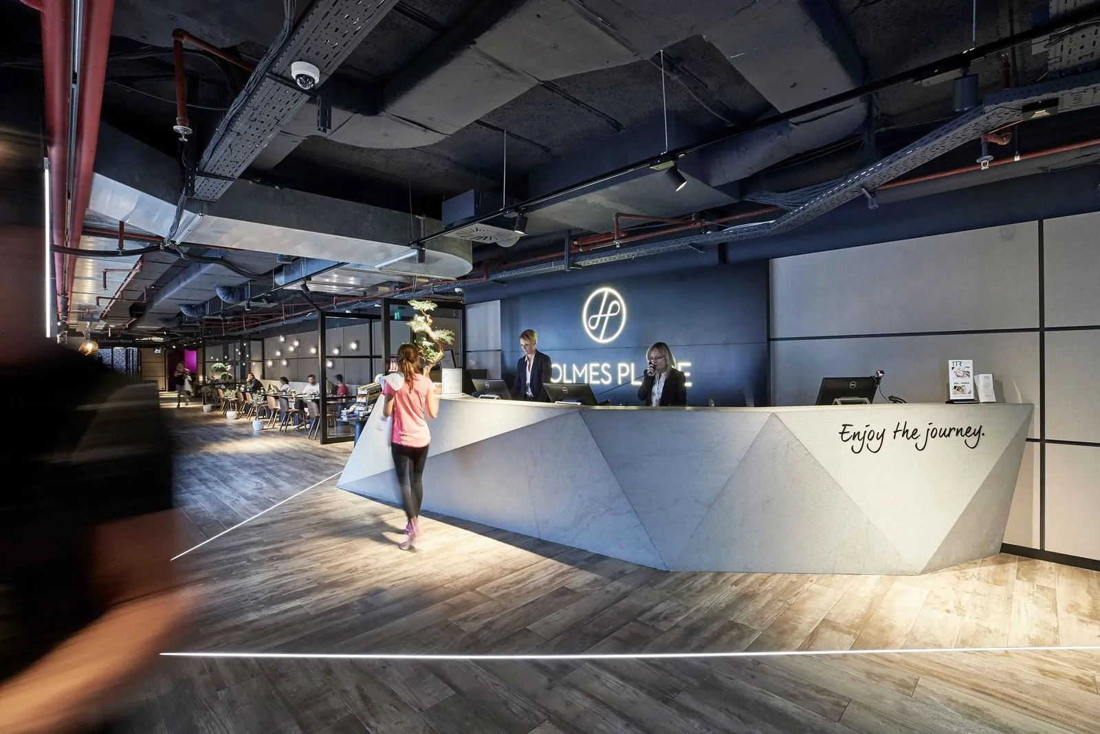 Moderner Empfangstresen im Holmes Place Fitnessstudio mit freundlichem Personal und einladender Atmosphäre.