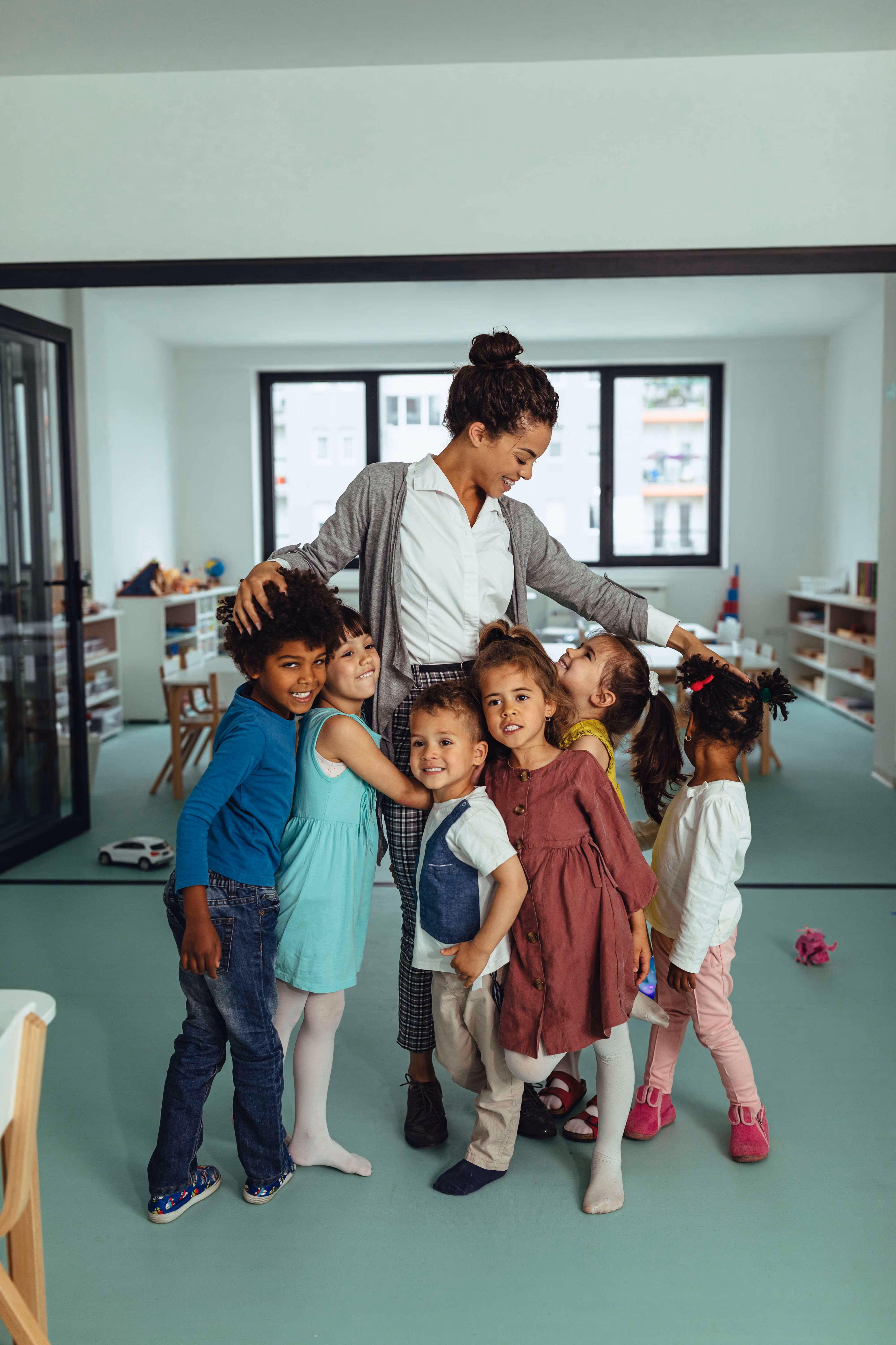 Unterschiedliche Kinder und eine Frau von Holmes Place arbeiten in einer fröhlichen Lernumgebung im Klassenzimmer zusammen.