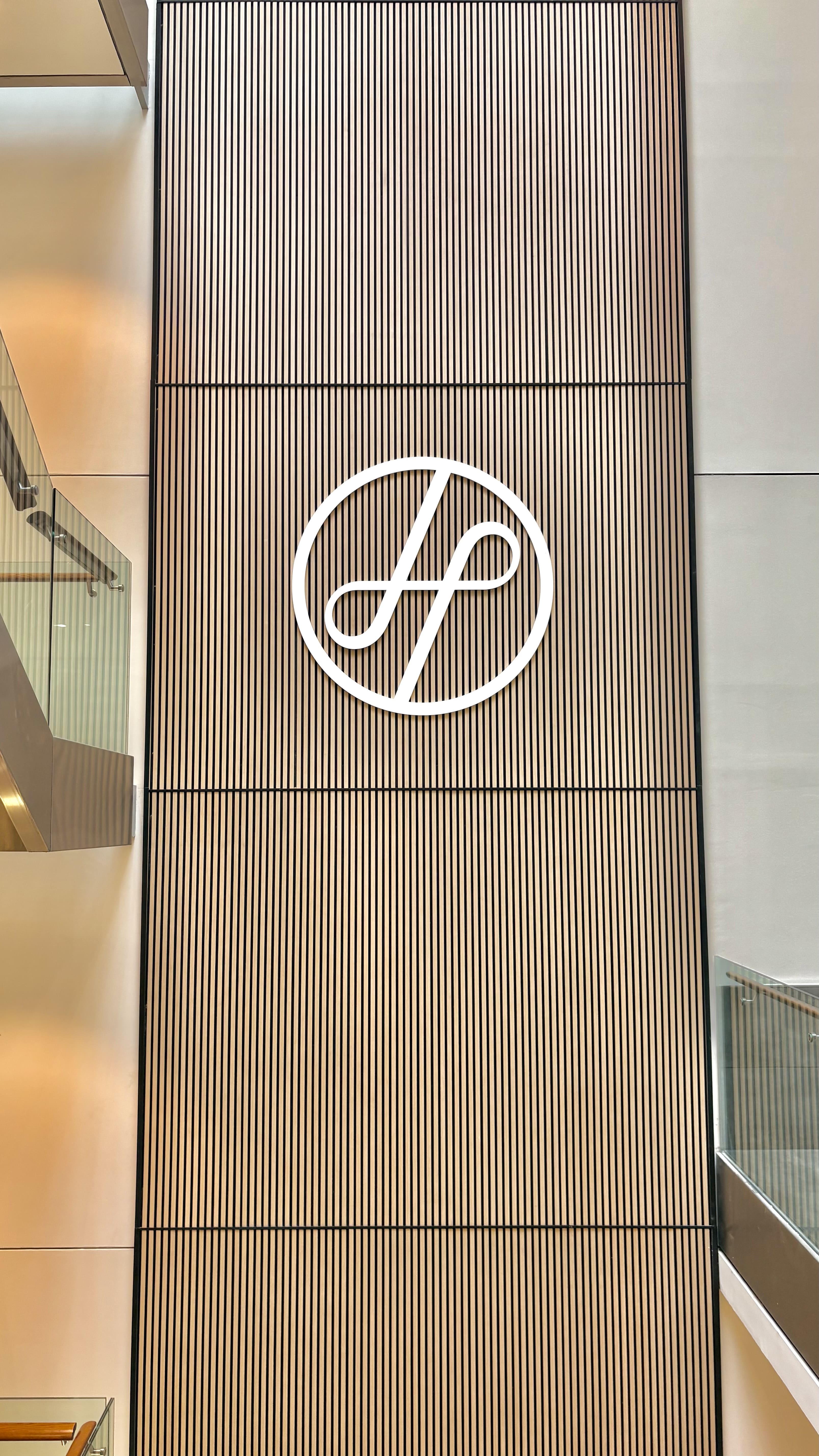 Logo des Fitnesscenters Holmes Place inmitten einer modernen Glastreppe und eleganter Innenarchitekturelemente.
