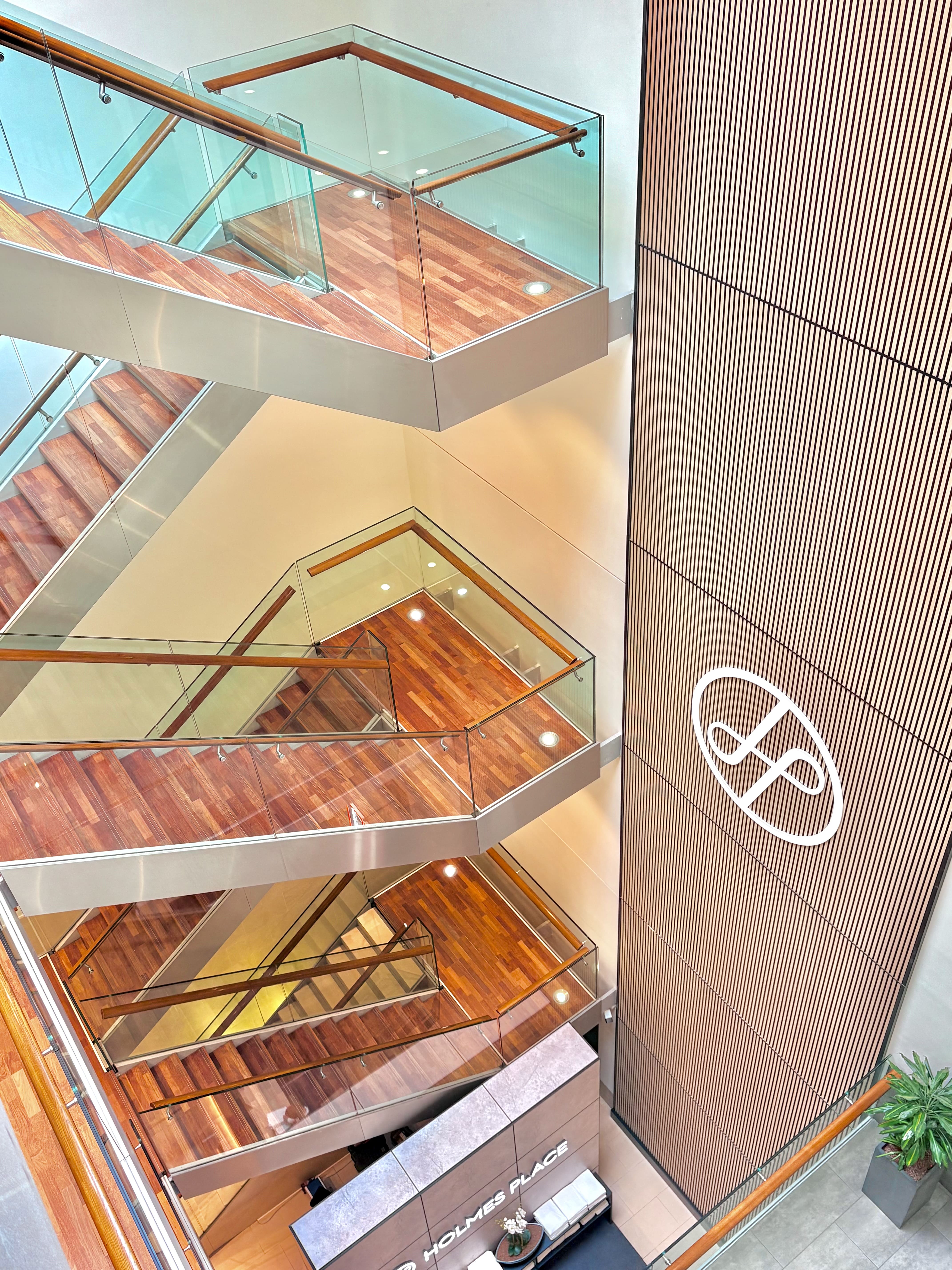 Modernes Treppendesign von Holmes Place mit Glasgeländern und Holzstufen in eleganter Innenatmosphäre.