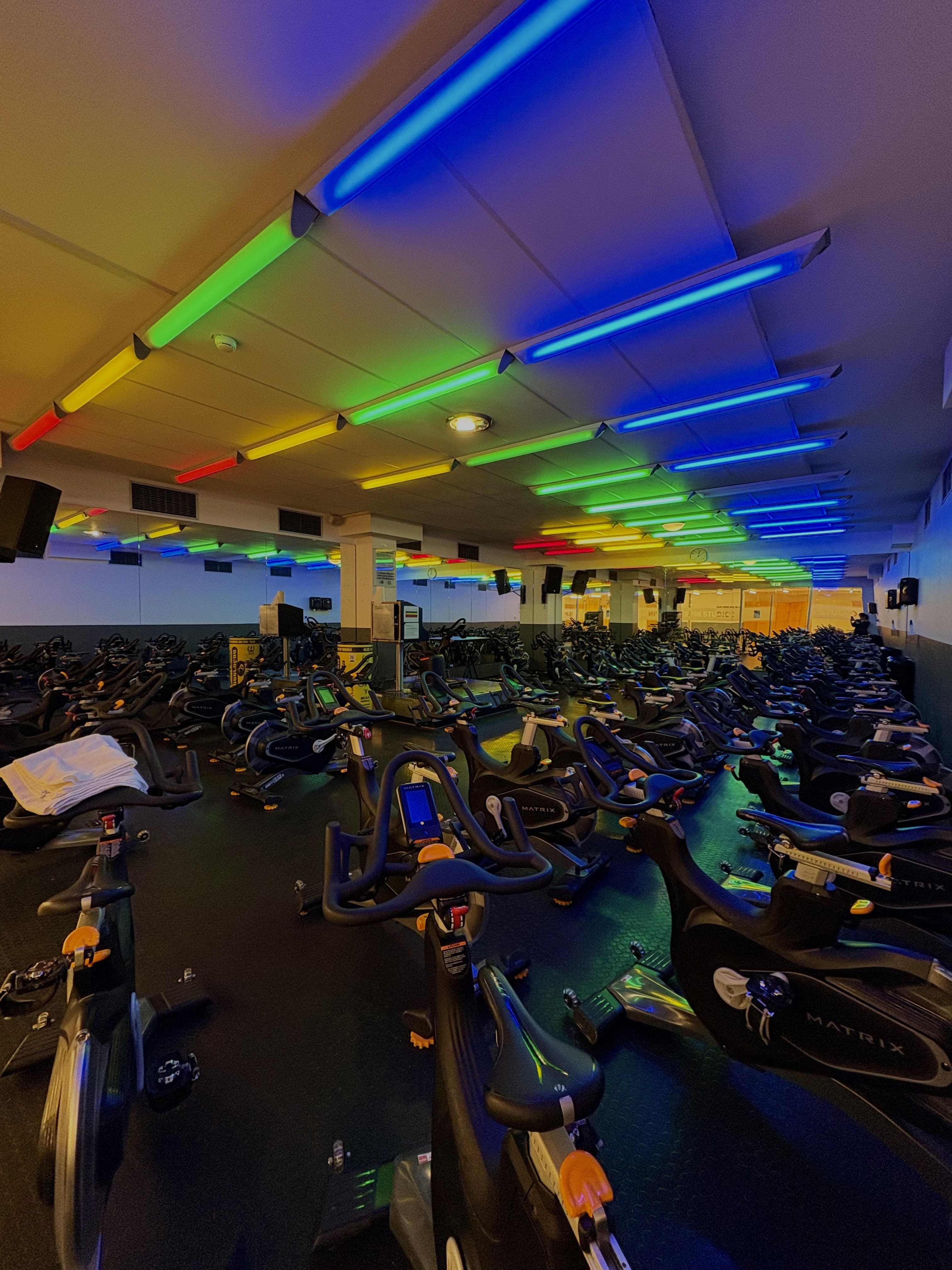 Indoor-Cycling-Studio Holmes Place mit Matrix-Heimtrainern und farbenfroher LED-Beleuchtung.