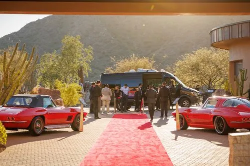 Red carpet event with classic red Corvettes and a black van
