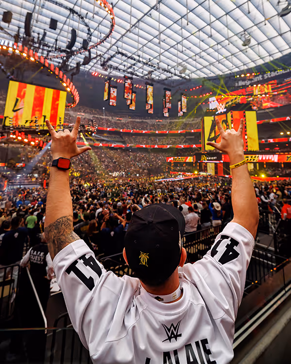 WWE fan raises hands in packed stadium during exciting wrestling event