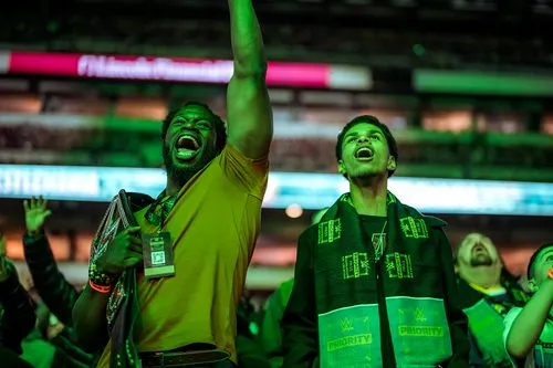 Fans cheering with excitement at a WWE event, bathed in green light