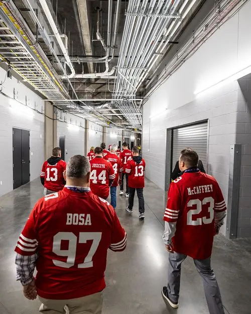Football players in red jerseys walking down industrial-looking hallway