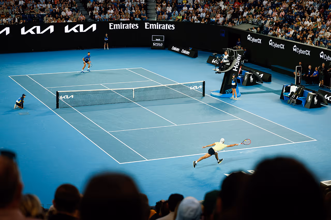 Tennis player stretches for ball on blue court at Australian Open tournament