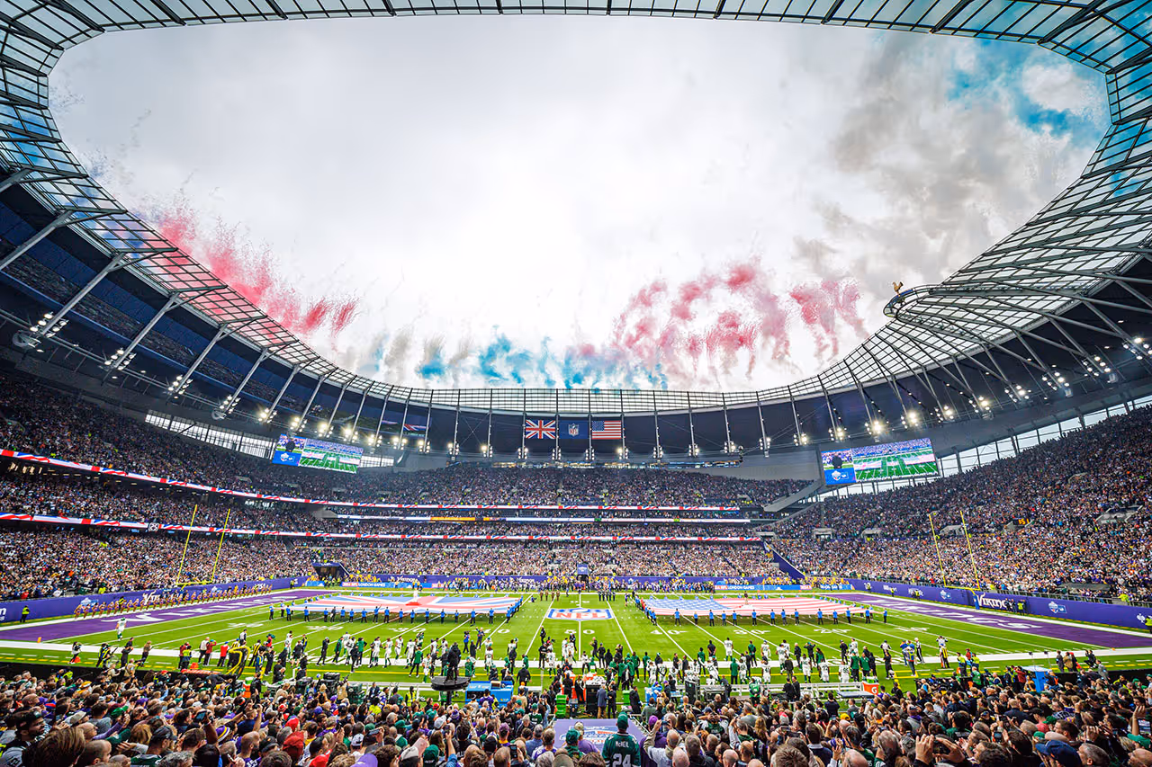 Packed NFL stadium with colorful smoke during pre-game ceremony