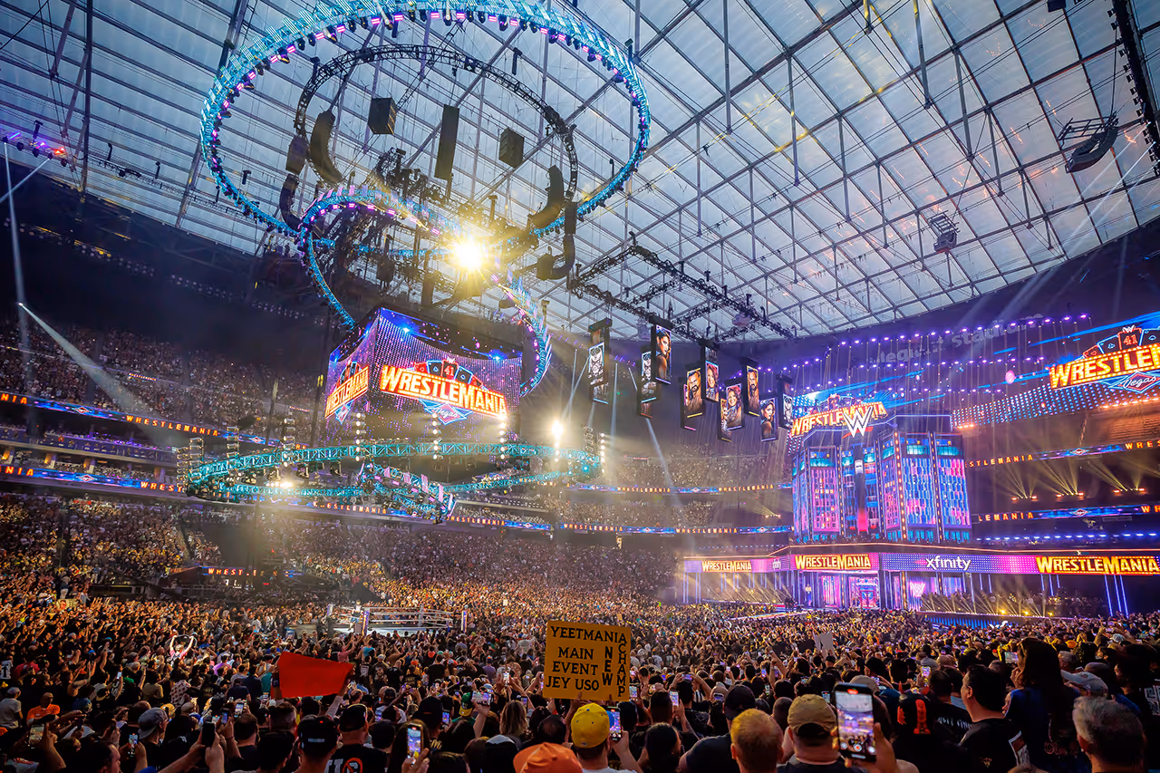 Packed WrestleMania stadium with colorful lights and massive video screens