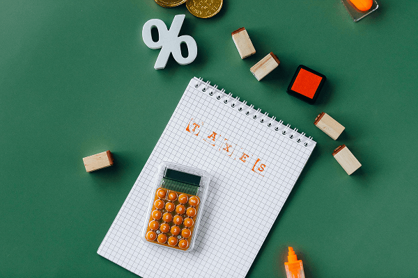 A calcutaor on a white notebook, with a percentage signe on the side, on a green background
