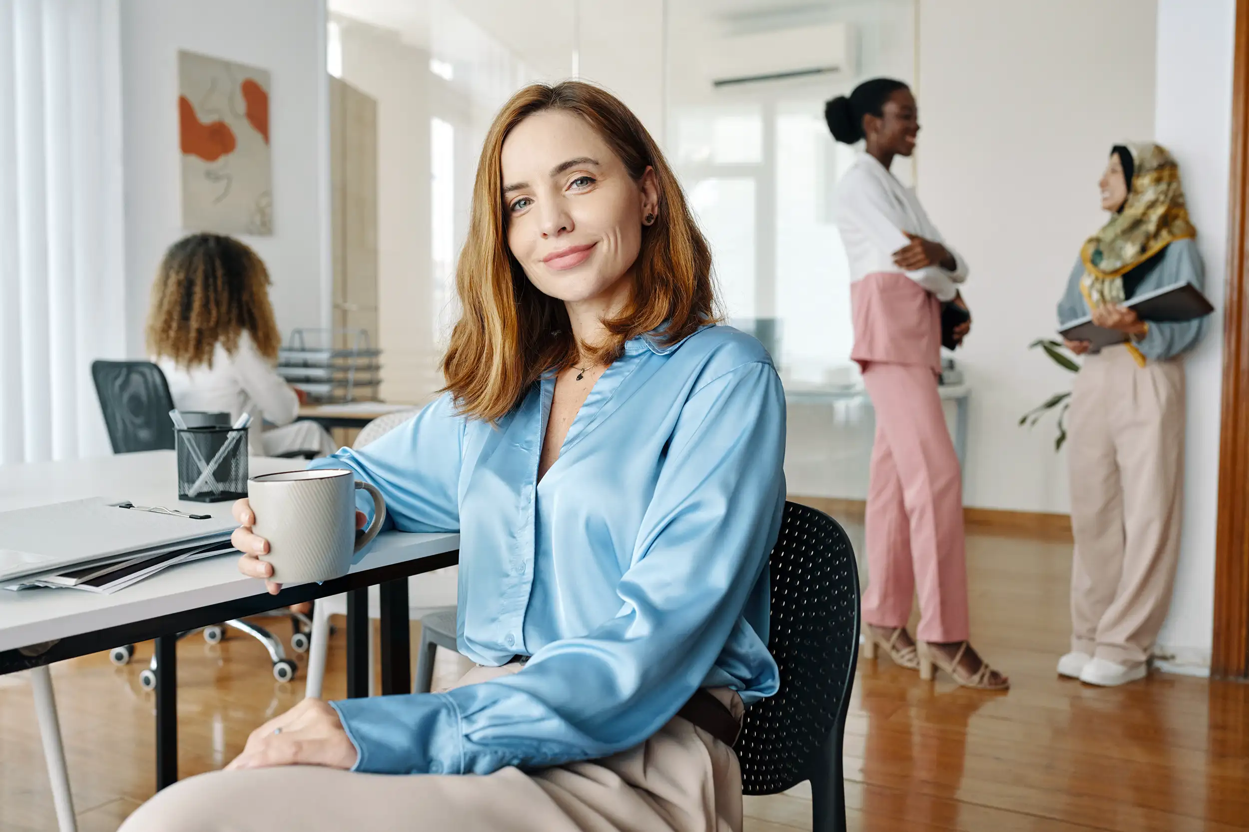 Business woman sitting with colleagues, looking at the camera.