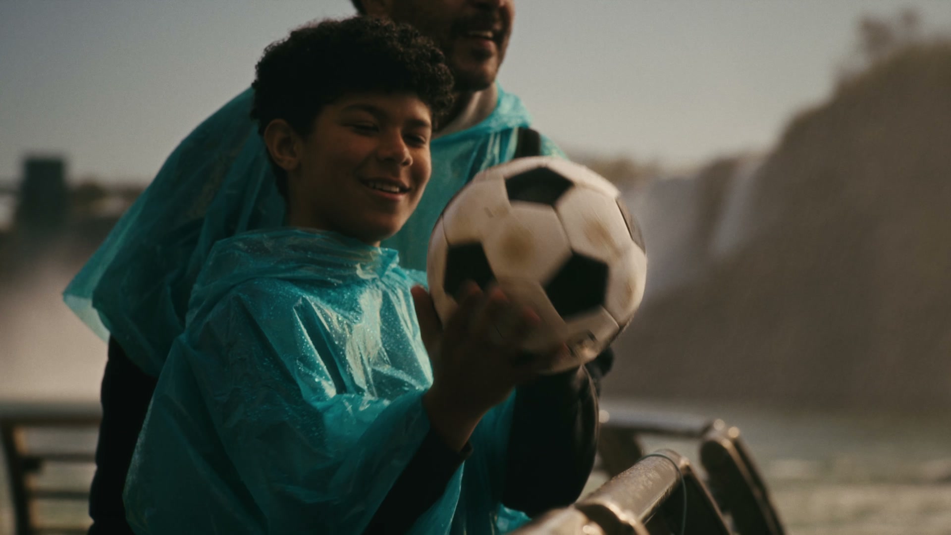 Boy in a poncho holding a soccer ball with his father at Niagara Falls, from the Niagara Parks FIFA World Cup 2026 campaign film