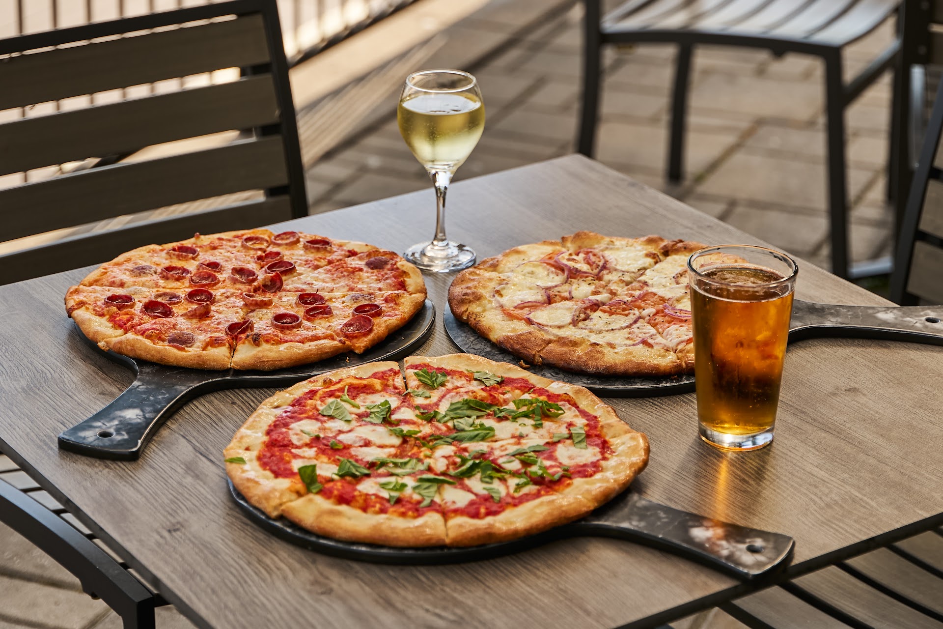 Fresh pizzas and drinks on a patio table at Bella Vista Ristorante