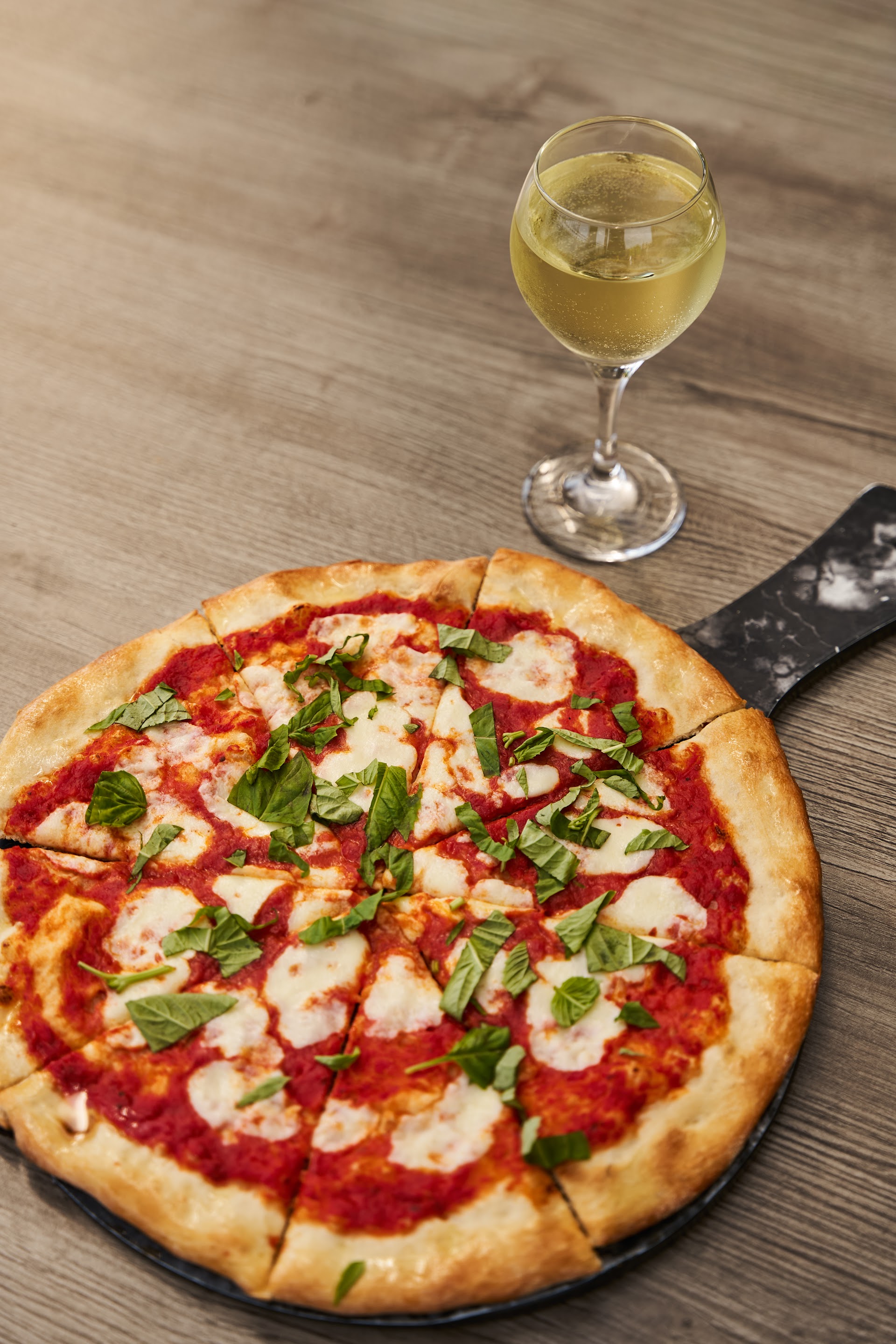 Margherita pizza with a glass of white wine at Bella Vista, home of the softest pizza dough in the city