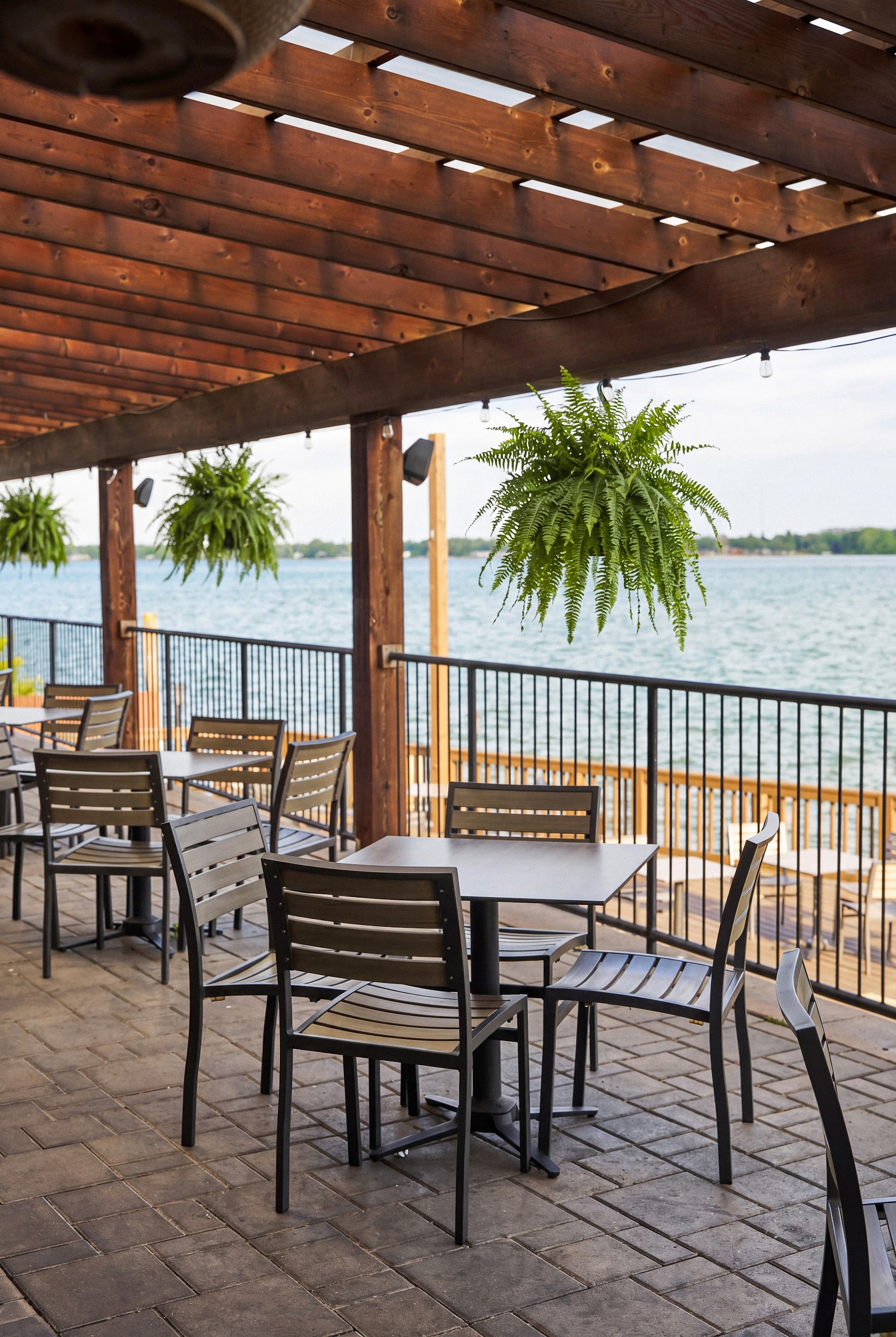 Bella Vista's covered waterfront patio with hanging plants and tables ready for service