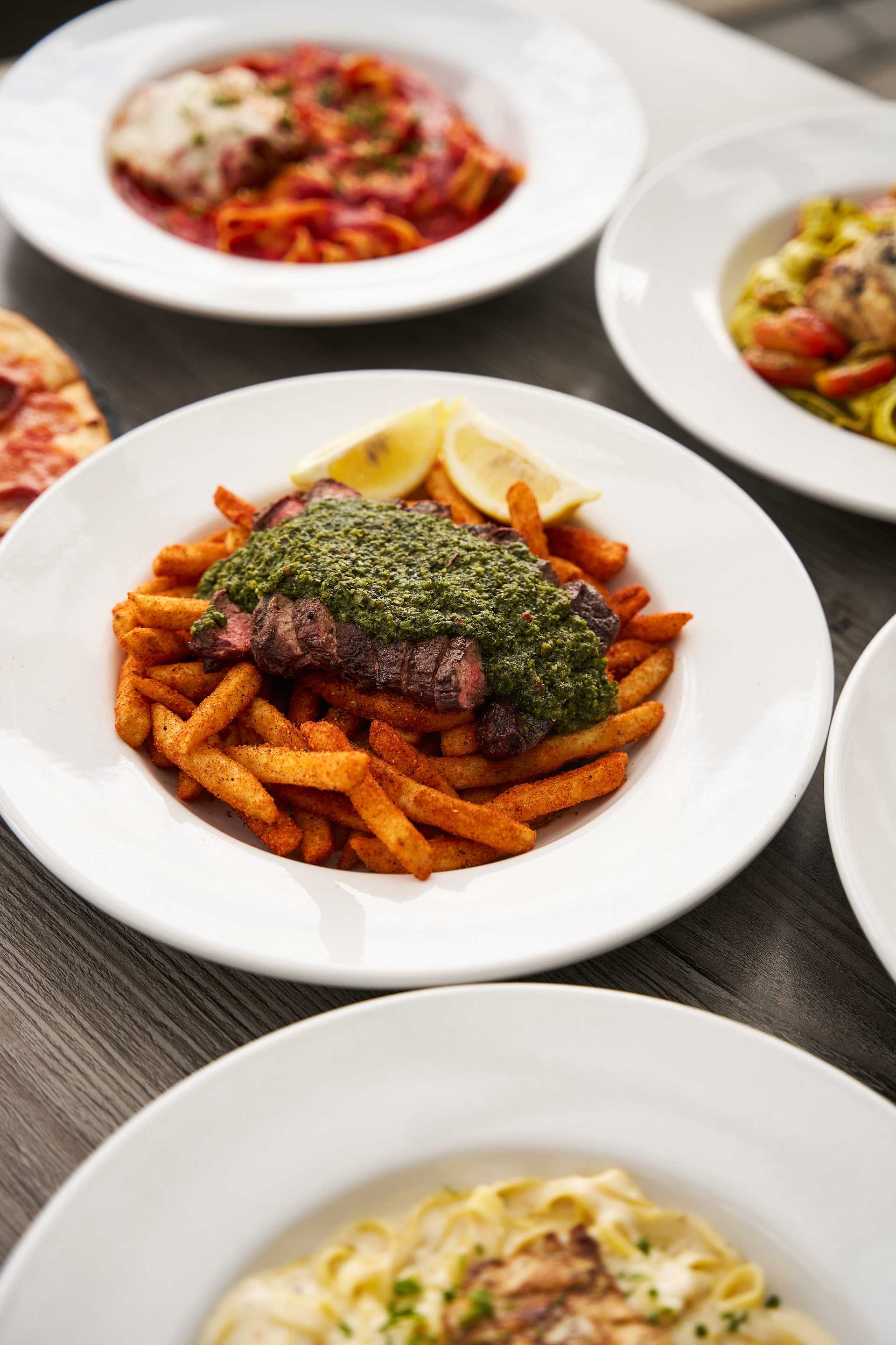 Steak frites and pasta plates filling a table at Bella Vista