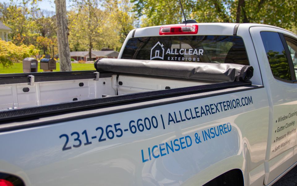 Back and side of white All Clear Exteriors truck with phone number and services listed.