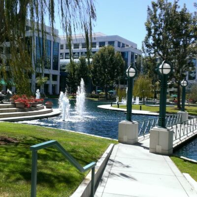 Daytime view of Water Garden landscaped pond, fountains, and pedestrian bridge surrounded by offices